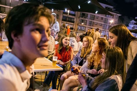 Dominee Baardmans in gesprek met jongeren op een terras, met een biertje en bitterbal.