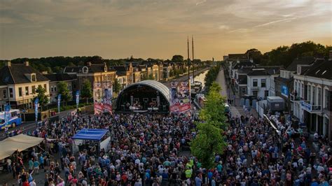 Een artistieke impressie van een festivalterrein met muziekpodium en mensen die samenkomen.
