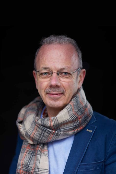 Foto van ds. Herman de Vries, staand voor een kerkgebouw.