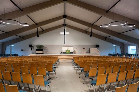 Interieurfoto van de vernieuwde kerkzaal met stoelen in halve cirkel en houten kruis