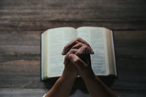 illustratie van een open Bijbel met handen die eromheen gevouwen zijn