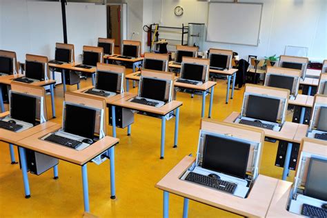 Een foto van een modern computerlokaal met leerlingen die werken op laptops.