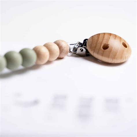 Een speenkoord met houten kralen in zachte kleuren, met een gepersonaliseerde naam, als voorbeeld van een schattig cadeau voor baby's.