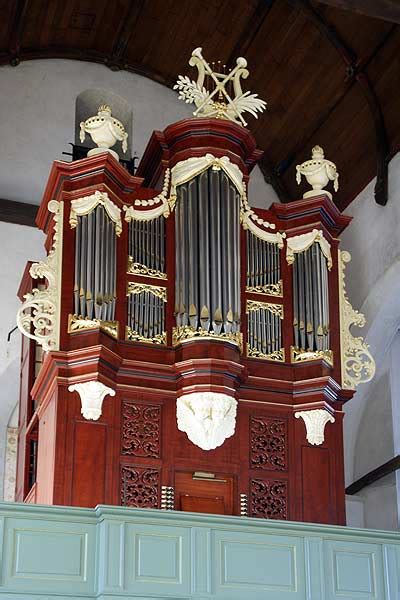 Gedetailleerde foto van het Houben-orgel in Sprang, met nadruk op het rijke houtsnijwerk en de orgelpijpen.
