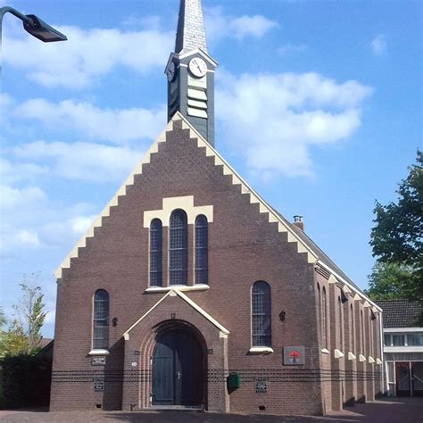 detail van de voorgevel van de Gereformeerde Kerk Wijnjewoude met rondboogramen en stichtingssteen