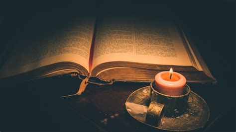 Interieur van een kerk met brandende kaarsen en een open Bijbel