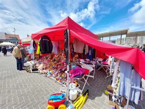 Een sfeerfoto van een drukke rommelmarkt met veel bezoekers en kramen
