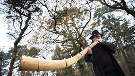 Foto van een persoon die een midwinterhoorn blaast in een winterse setting.