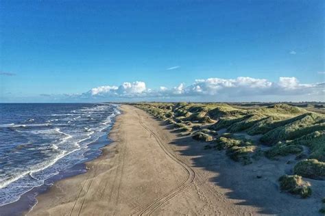Landschapsfoto die de diversiteit van het Nederlandse kustgebied weergeeft, met duinen, strand en zee.